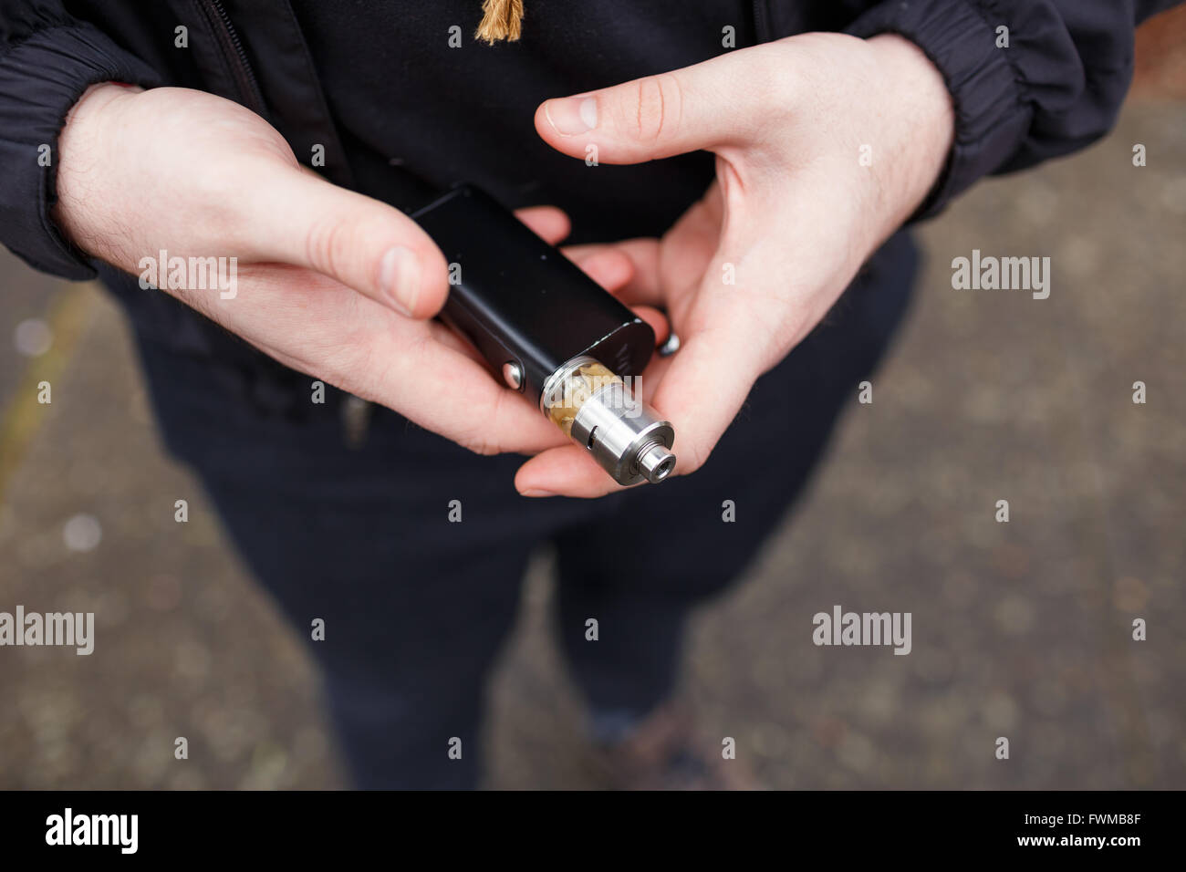 Urban lifestyle portrait of a man vaping in an urban environment with a custom vape mod device. Stock Photo