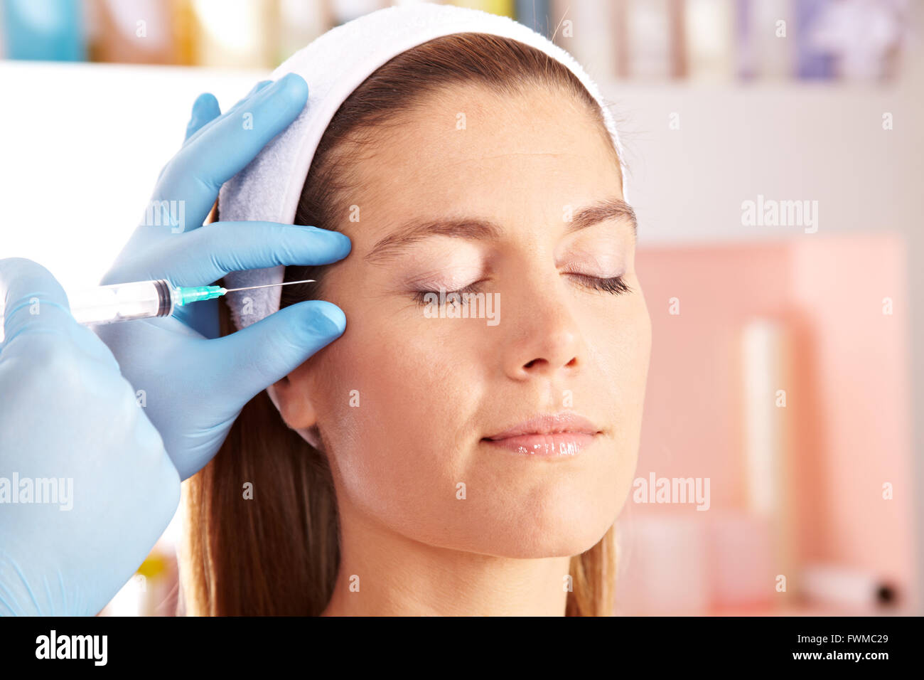 Woman in beauty clinic getting botox injection to remove eye wrinkles Stock Photo