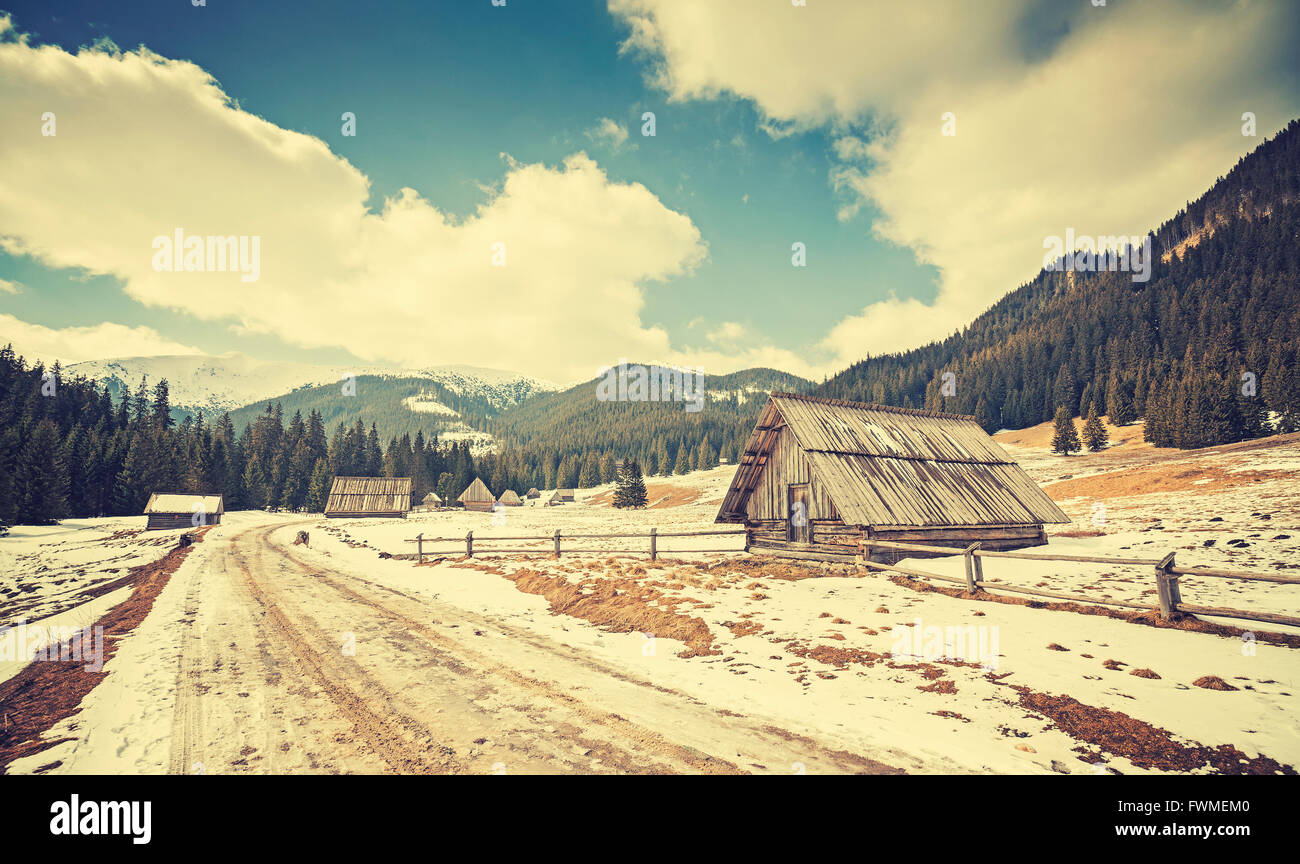 Vintage toned wooden huts by a road in Tatra Mountains, end of winter and beginning of spring, Poland. Stock Photo