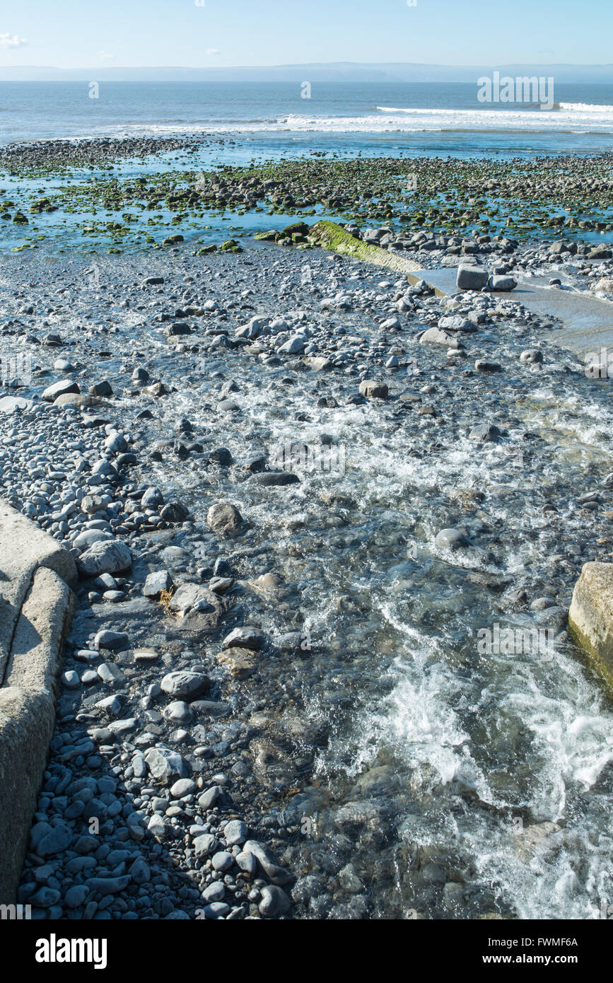 The end of a journey. The River Col-huw runs down a pebble beach to the sea. Stock Photo