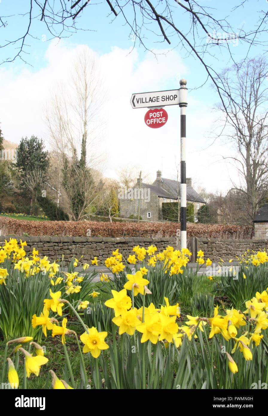A signpost on the village green in Baslow, Derbyshire points the way to the post officeand village shop, Peak District,UK -April Stock Photo