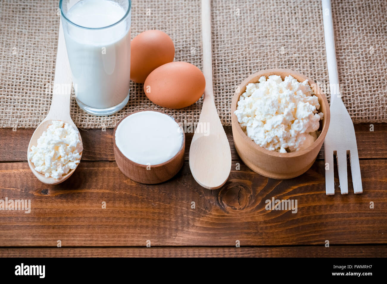 Dairy products on wooden table. Sour cream, milk, cheese, yogurt and eggs. Top view with copy