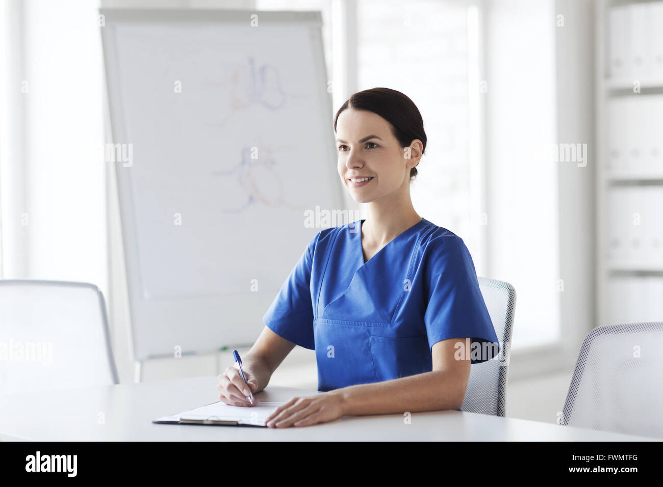 happy female doctor or nurse writing to clipboard Stock Photo - Alamy
