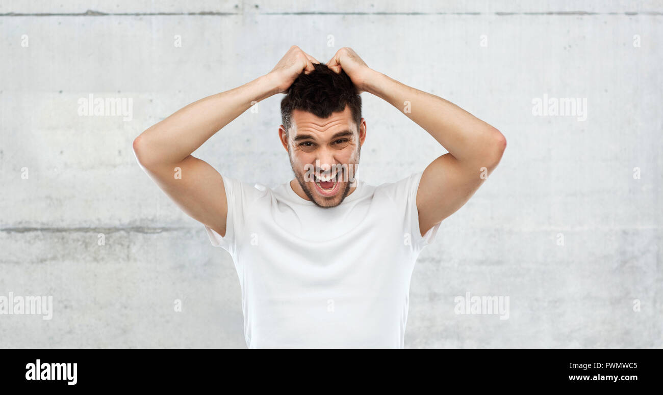 crazy shouting man in t-shirt over gray background Stock Photo