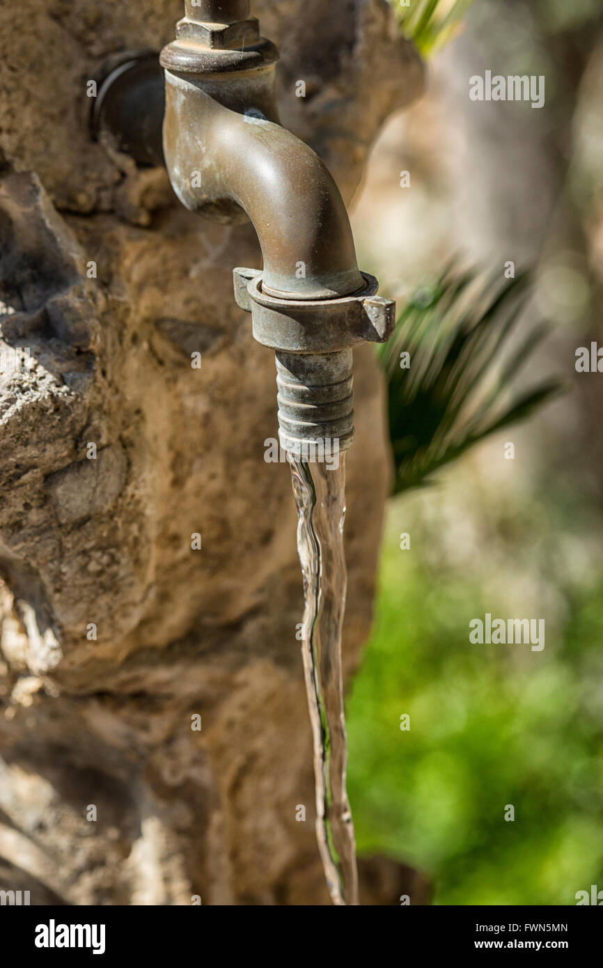 Old copper water tap with running water in garden Stock Photo