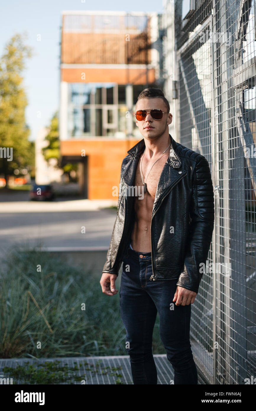 Muscular man in leather jacket and sunglasses. Industrial portrait. Stock Photo