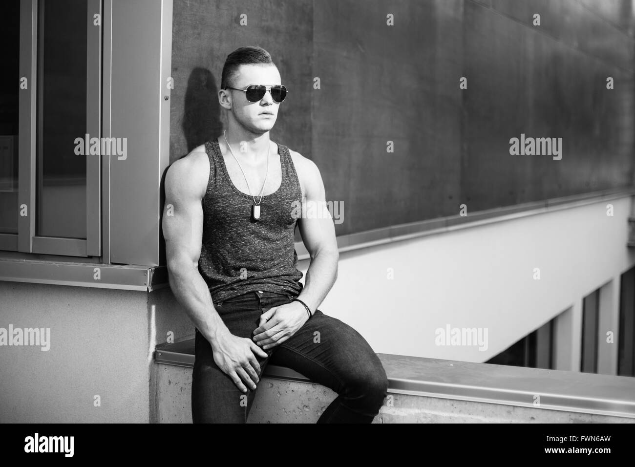 Muscular man posing near building. Black and white. Stock Photo