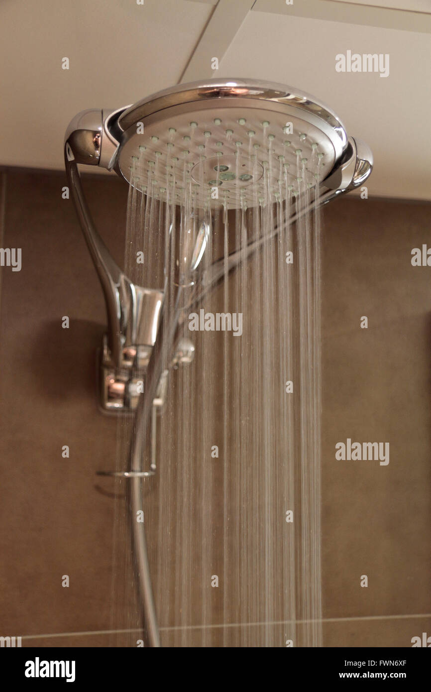 A large spray shower head with running water in a hotel bathroom in the Netherlands.. Stock Photo