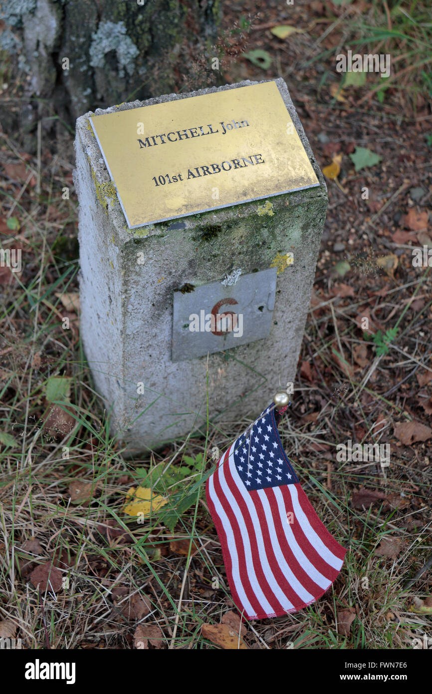 An American flag beside one marker in the Bois de la Paix (the Wood of Peace), near Bastogne,Walloon, Belgium. Stock Photo