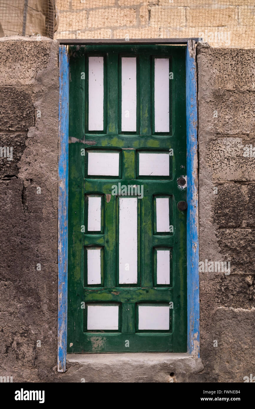 Rustic door. Panelled wooden door painted  green and white with blue frame in a breezeblock outside wall. Aldea Blanca, Tenerife Stock Photo