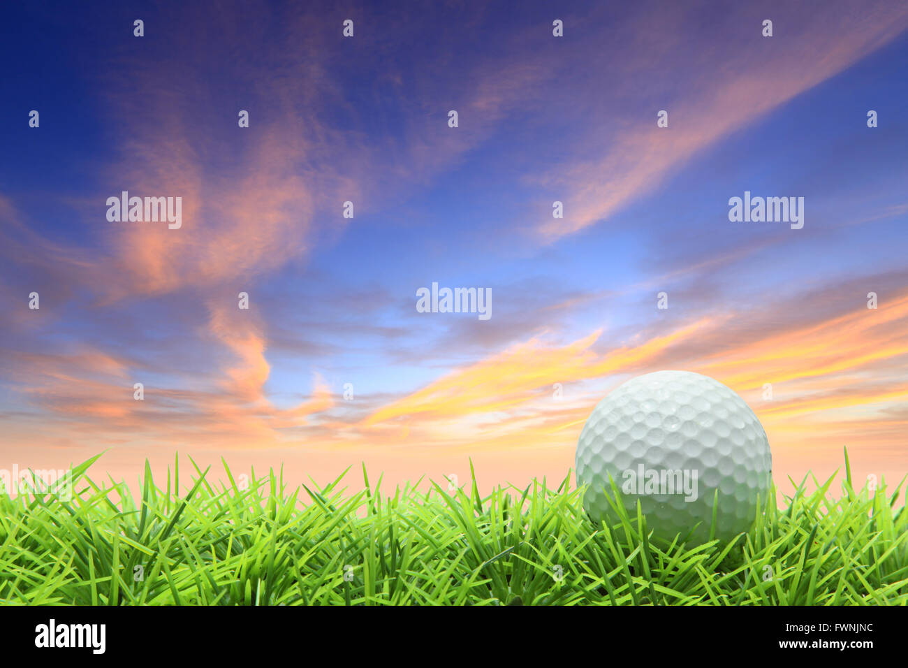 isolated golf ball on green grass over beautiful sky Stock Photo