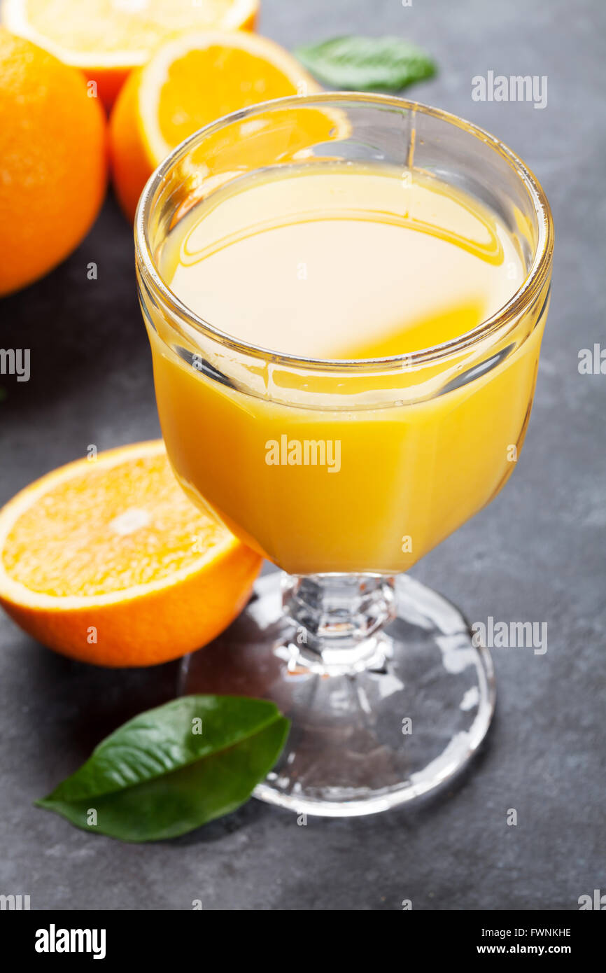 Fresh orange juice glass and fruits on stone table Stock Photo