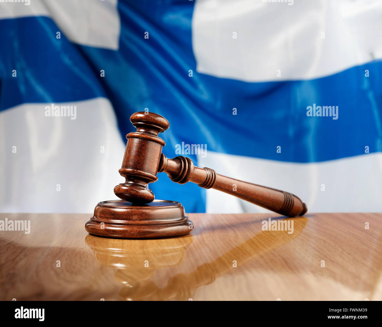 Mahogany wooden gavel on glossy wooden table, flag of Finland in the background. Stock Photo
