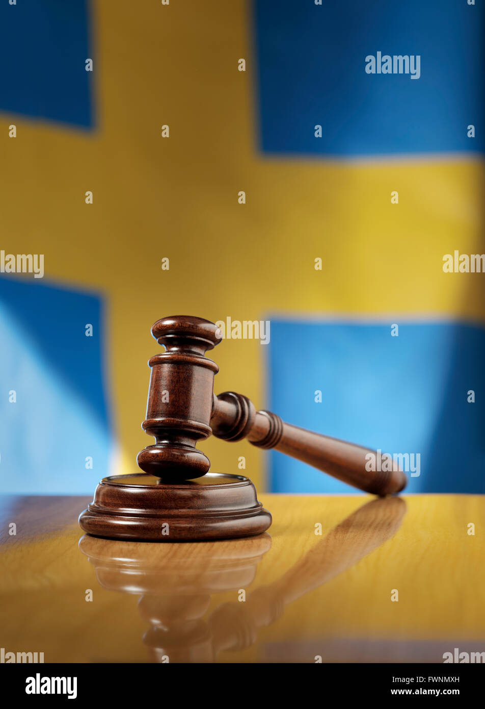 Mahogany wooden gavel on glossy wooden table, flag of Sweden in the background. Stock Photo