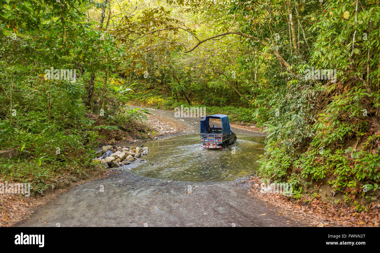 OSA PENINSULA, COSTA RICA - Truck fords stream on dirt road in rain forest. Stock Photo