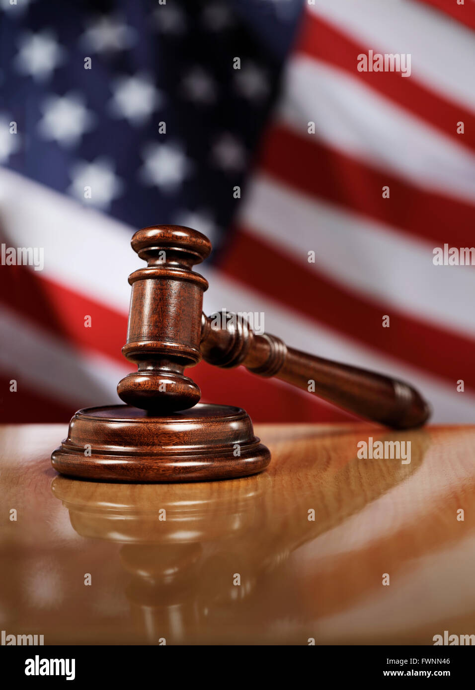 Wooden gavel on glossy table, The flag of USA in the background. Stock Photo