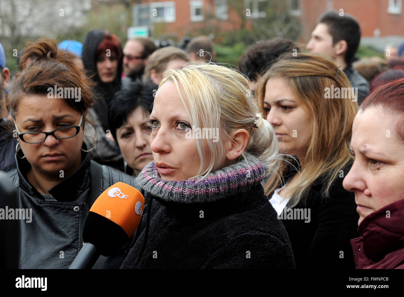 Lohne, Germany. 6th Apr, 2016. Roughly 60 employees and workers with service contracts standing in front of the town hall in Lohne, Germany, 6 April 2016. Romanian worker Victoria is giving an interview for a TV channel. Several production halls of the Wiesenhof group burned down entirely on Easter Monday. Numerous employees are now afraid to lose their jobs. PHOTO: INGO WAGNER/dpa/Alamy Live News Stock Photo