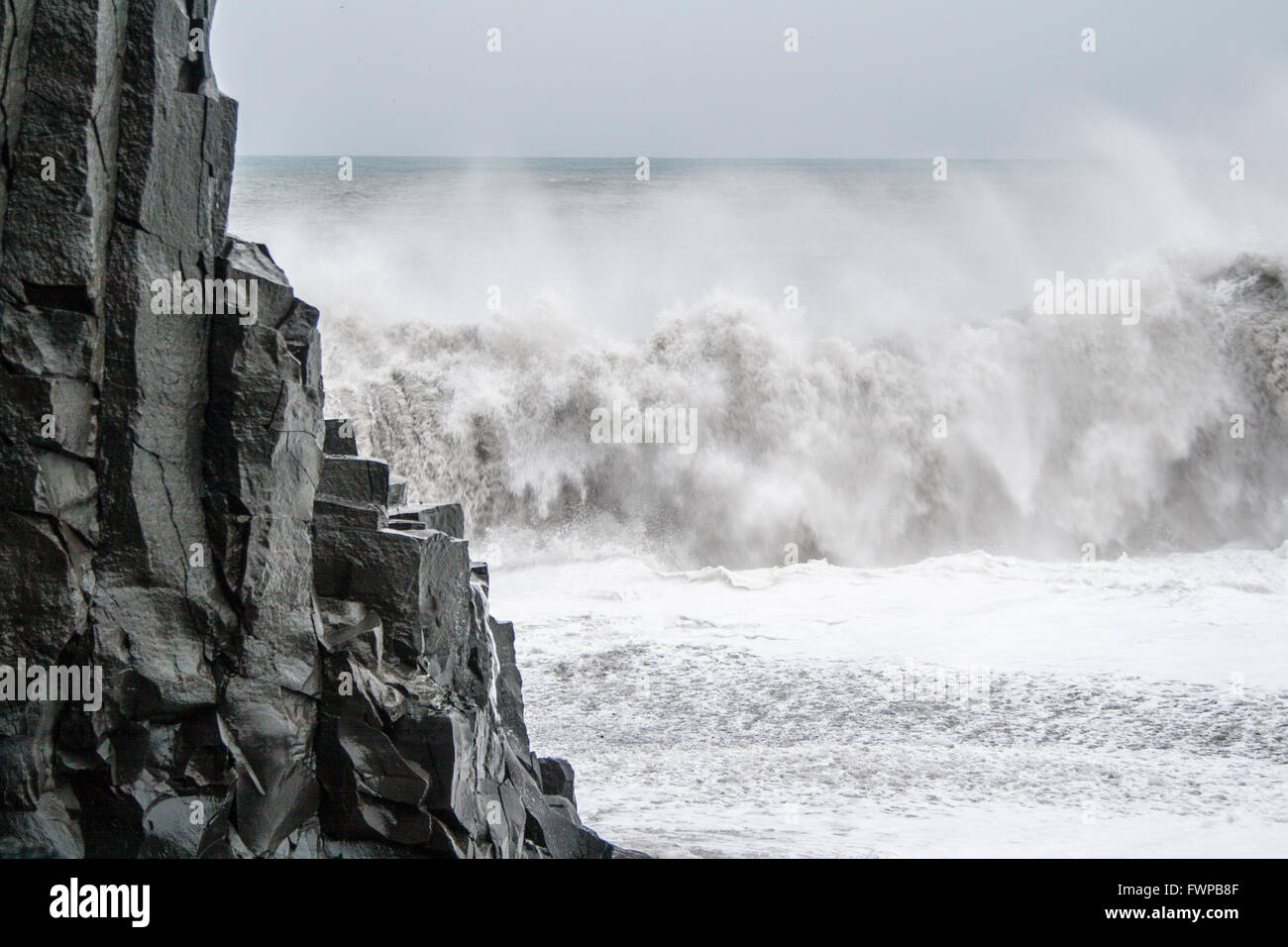Waves crashing behind basalt column at Reynisfjara beach, near Vik Stock Photo