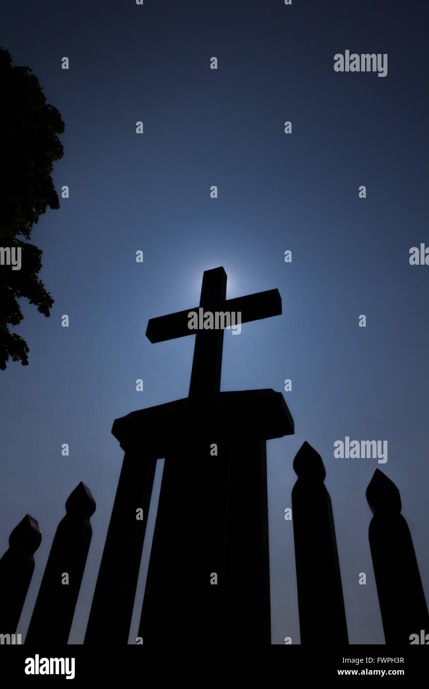 Small wooden black painted cross on the top of a fence, photographed from a low angle Stock Photo