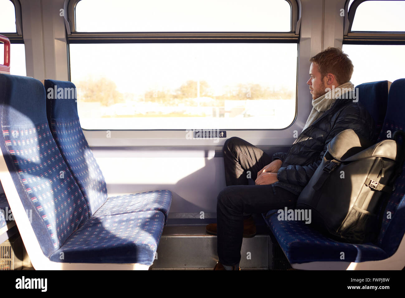 Young Man Sitting In Train Carriage On Railway Journey Stock Photo
