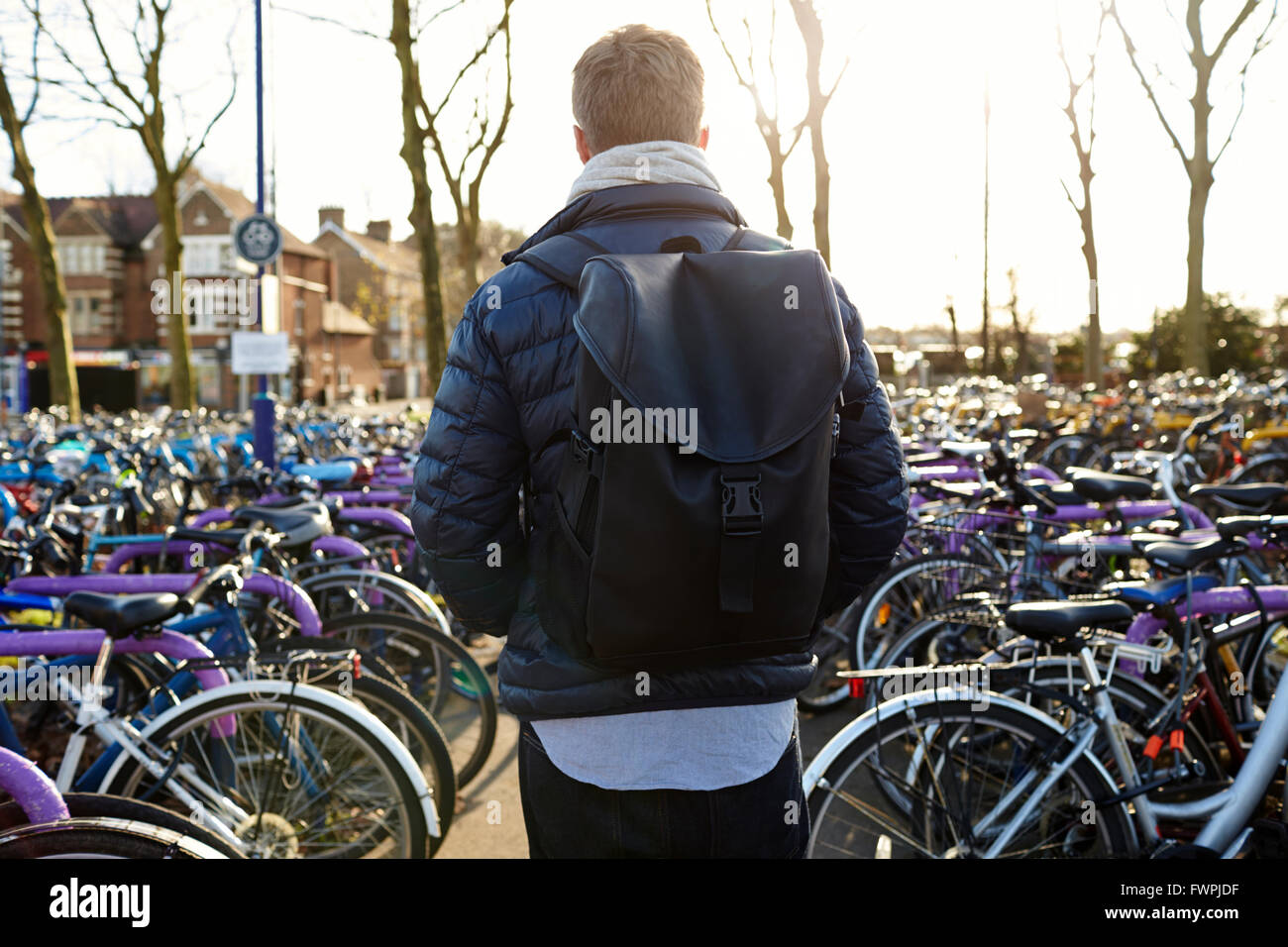 Rear View Of Man Leaving Bike In Cycle Park At Rail Station Stock Photo