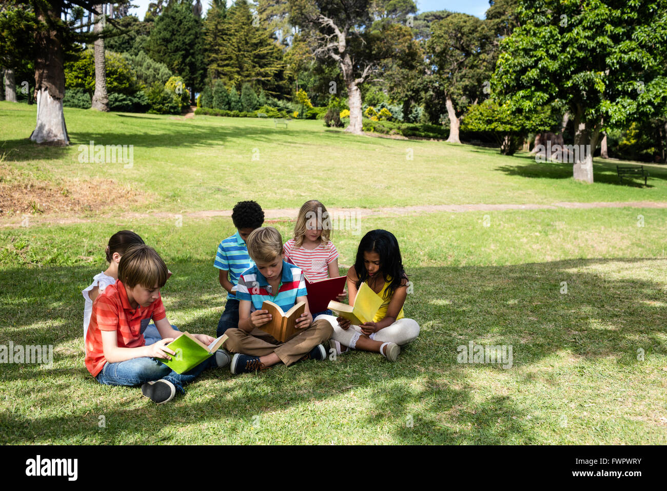Children reading book in the park Stock Photo Alamy