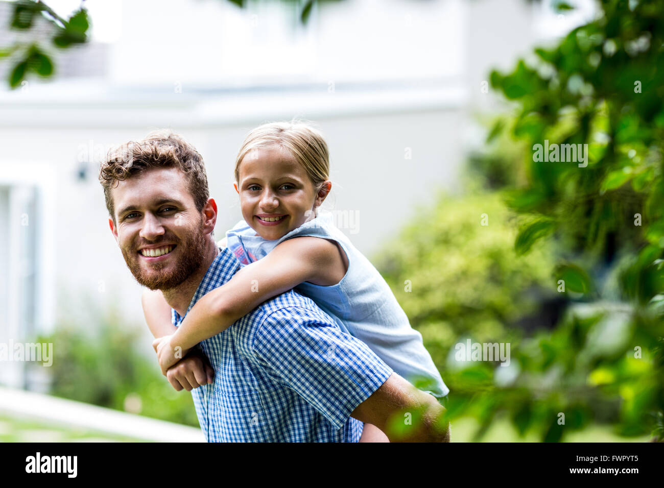 Smiling father carrying daughter in yard Stock Photo - Alamy