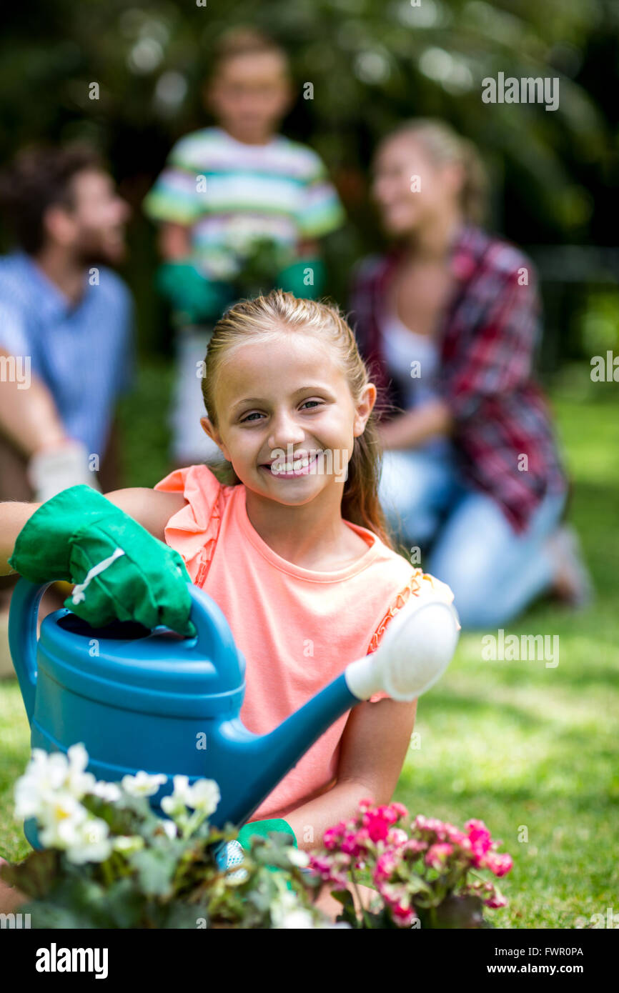 Smiling girl with watering can at yard Stock Photo - Alamy