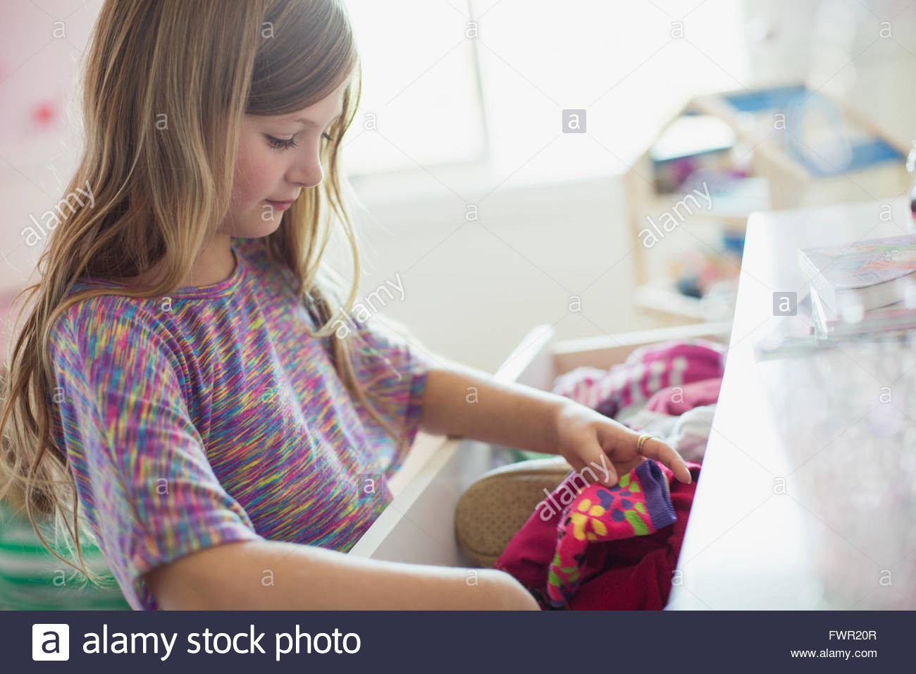 Little Girl Looking In Dresser Drawer At Home Stock Photo