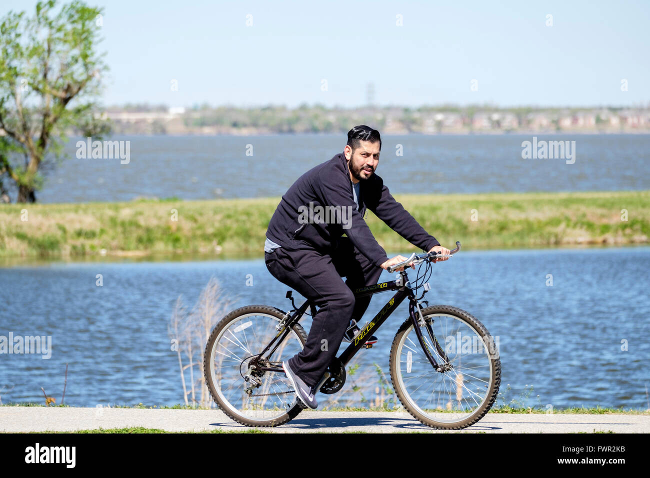 A Hispanic man bicycles for exercise on the trails next to the North Canadian river and Overholser Lake, Oklahoma City,USA. Stock Photo