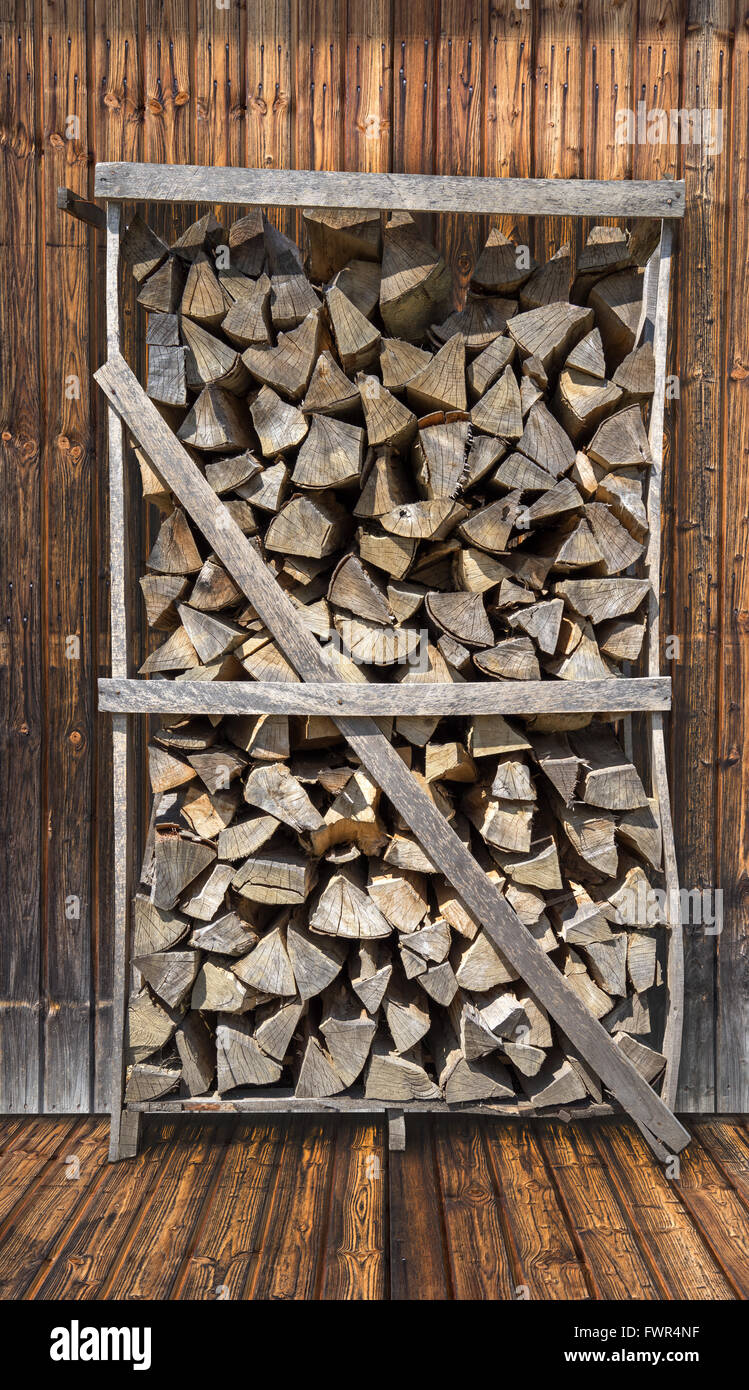 Firewood rack in front of a wooden wall Stock Photo