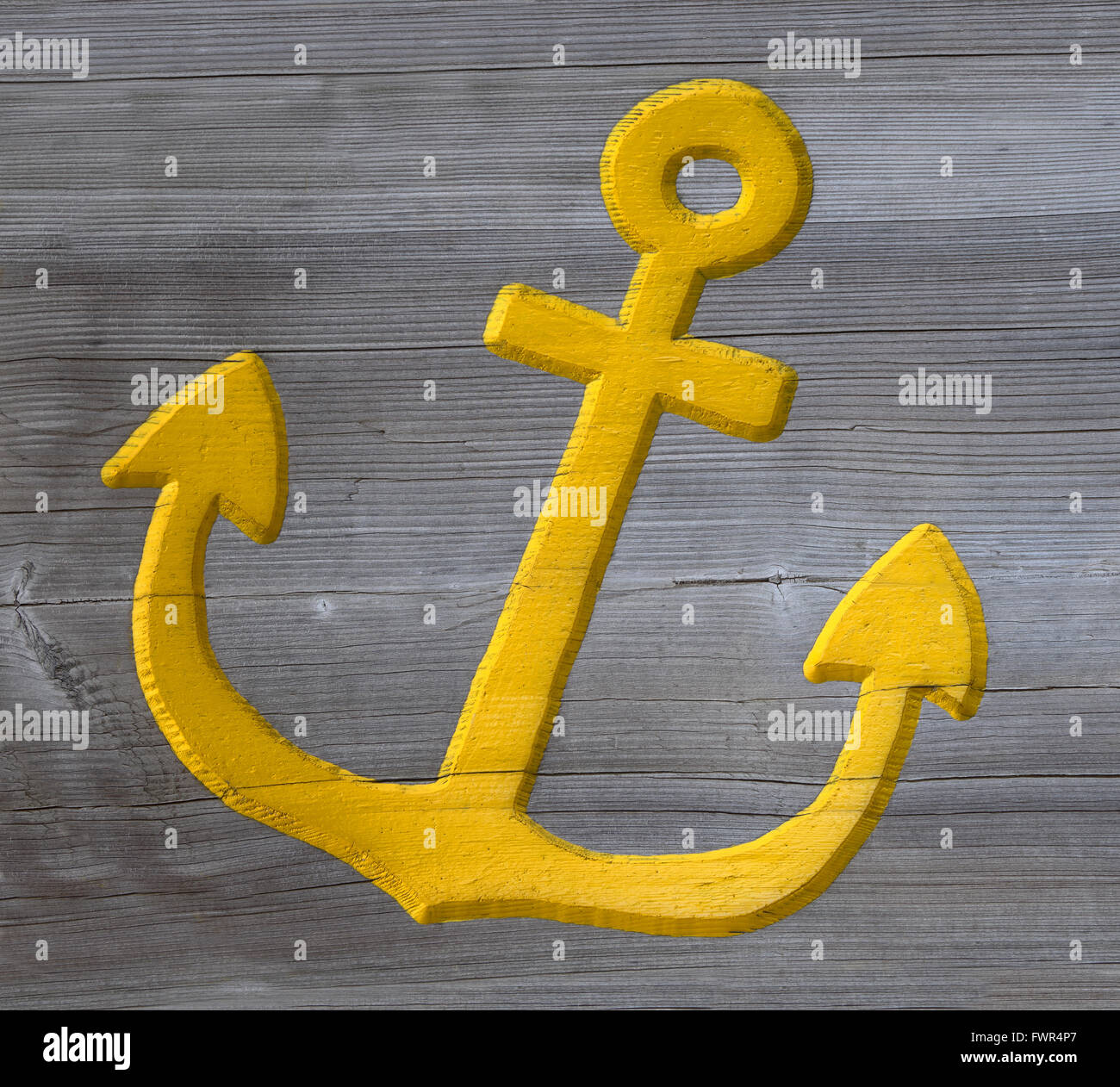 Yellow anchor carved in wood Stock Photo