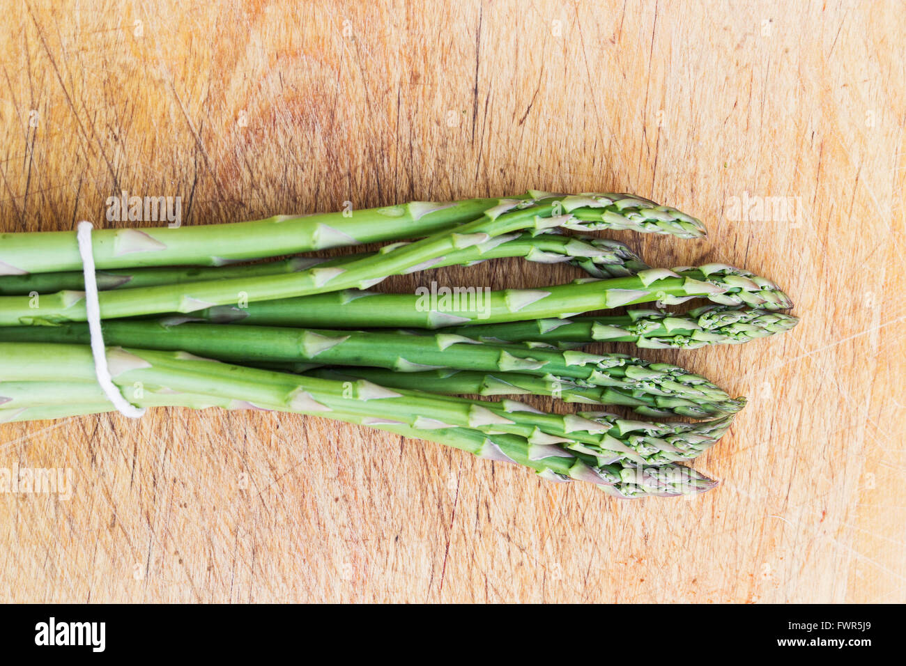 Spears of asparagus, Asparagus officinalis, tied on a chopping board