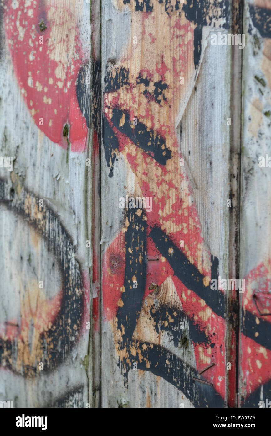 An Old Back Door Covered In Red Paint And Black Spray Paint Stock