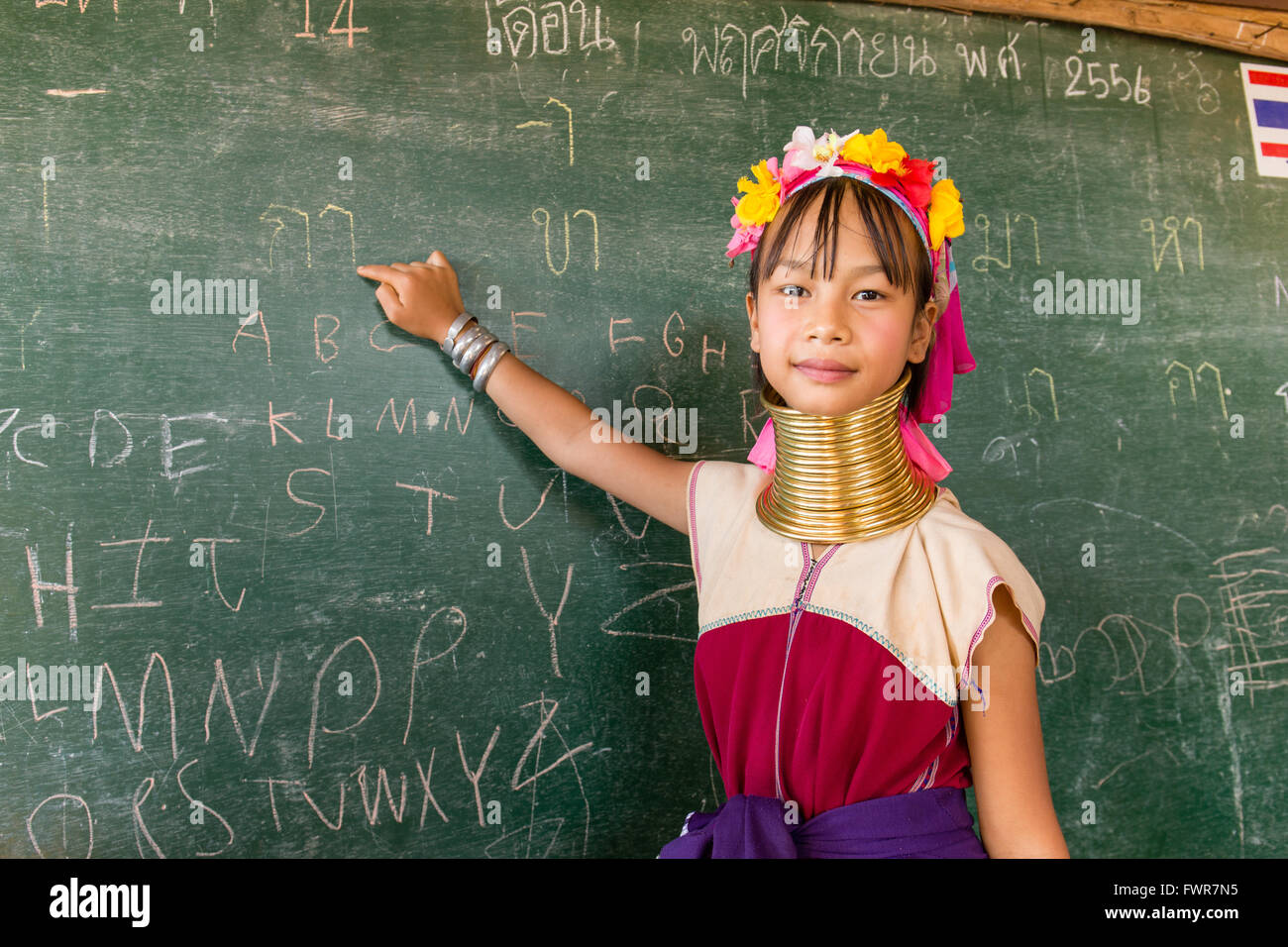 Girl with neck rings at school, Padaung hilltribe, long-necked women, schoolgirl pointing at a blackboard, Chiang Rai Province Stock Photo