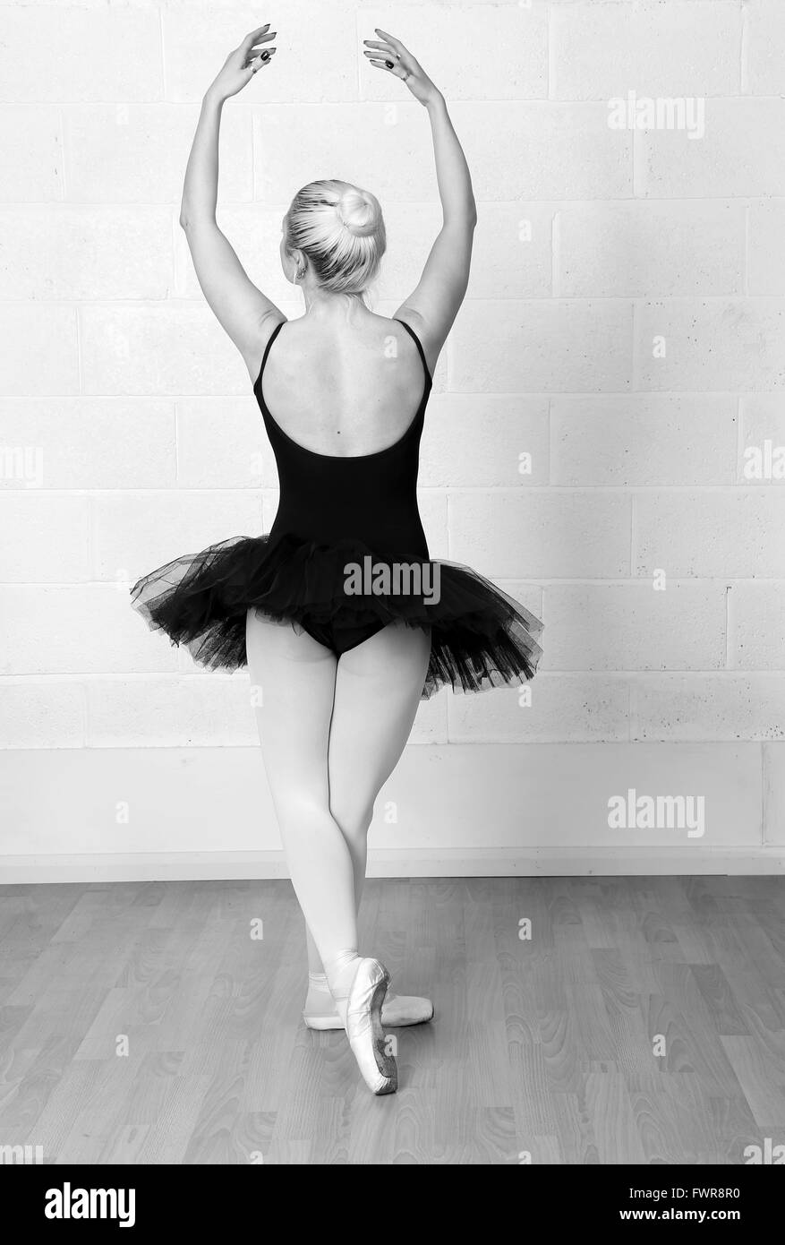 Young woman ballet dancer in a black tutu  practicing her moves in a studio. 5th April 2016 Stock Photo