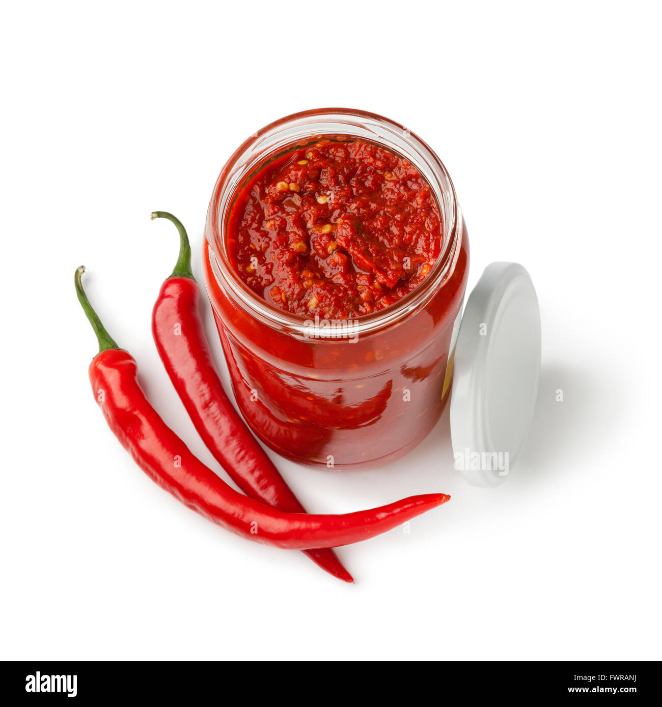 Glass jar with traditional Indonesian Sambal and fresh red chili peppers on white background Stock Photo