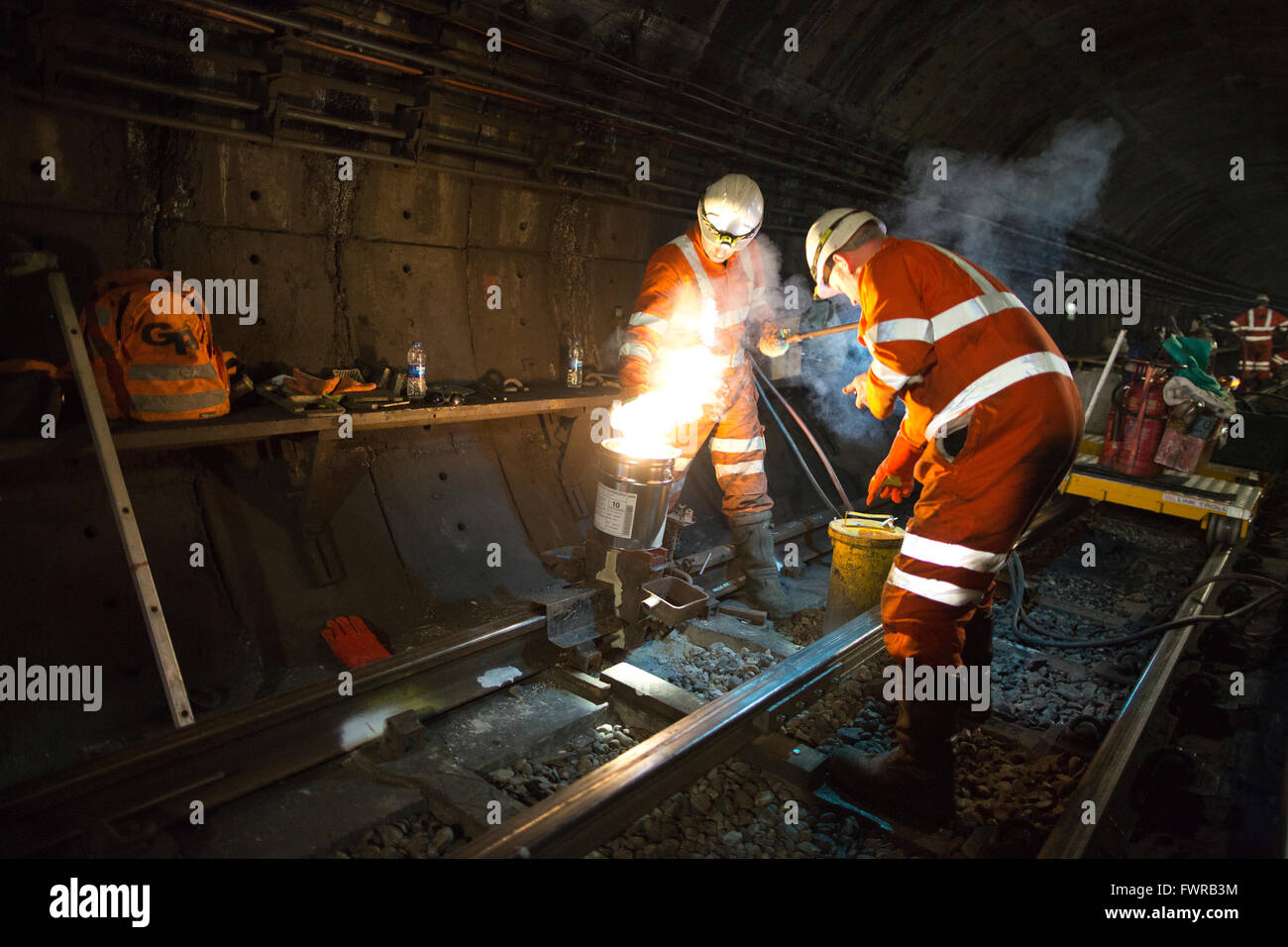 Engineers weld replacement track components together using thermite welding on London Underground rail track, London, UK Stock Photo