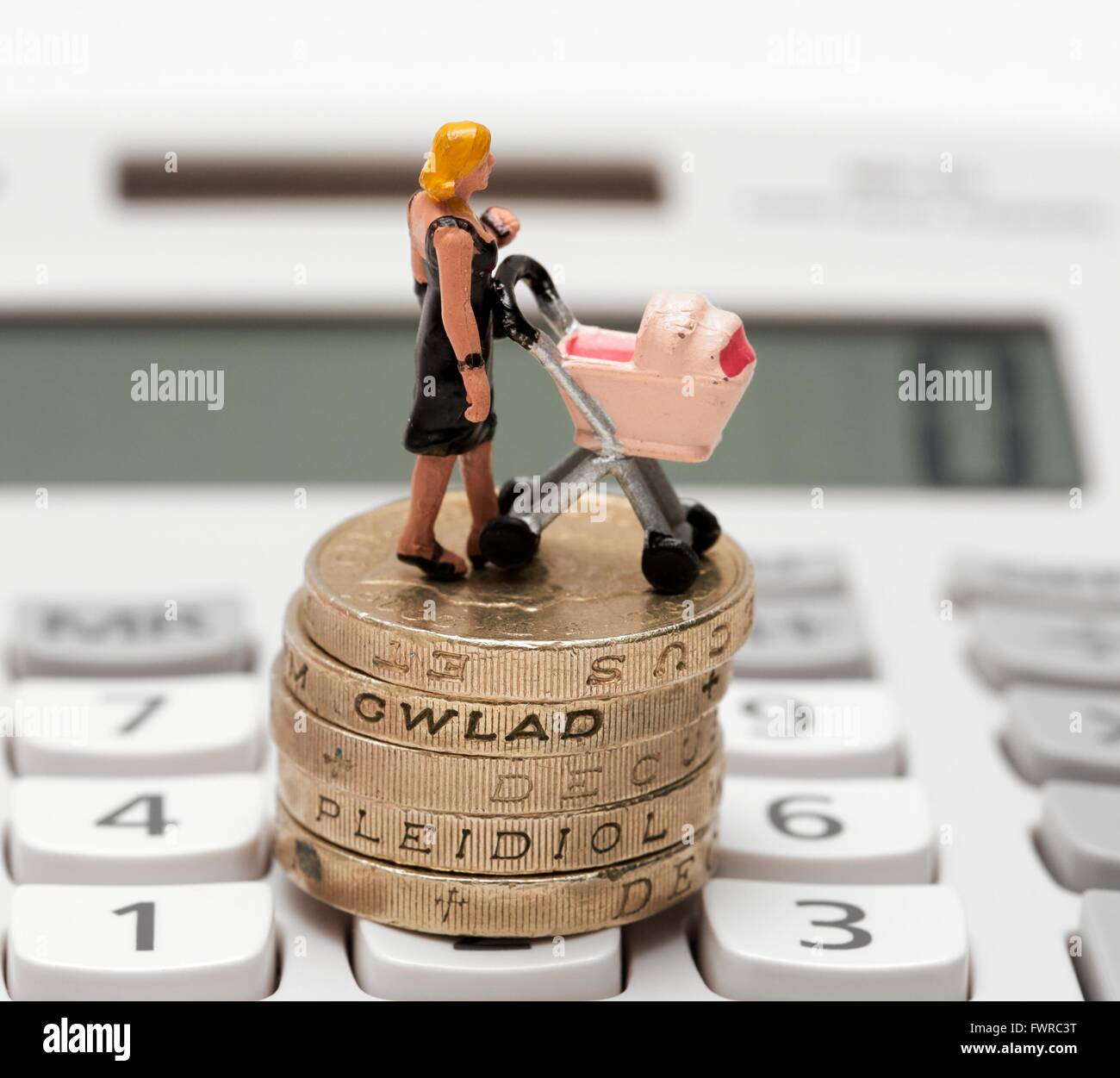A miniature figurine woman with a pram standing on top of one pound coins and calculator Stock Photo