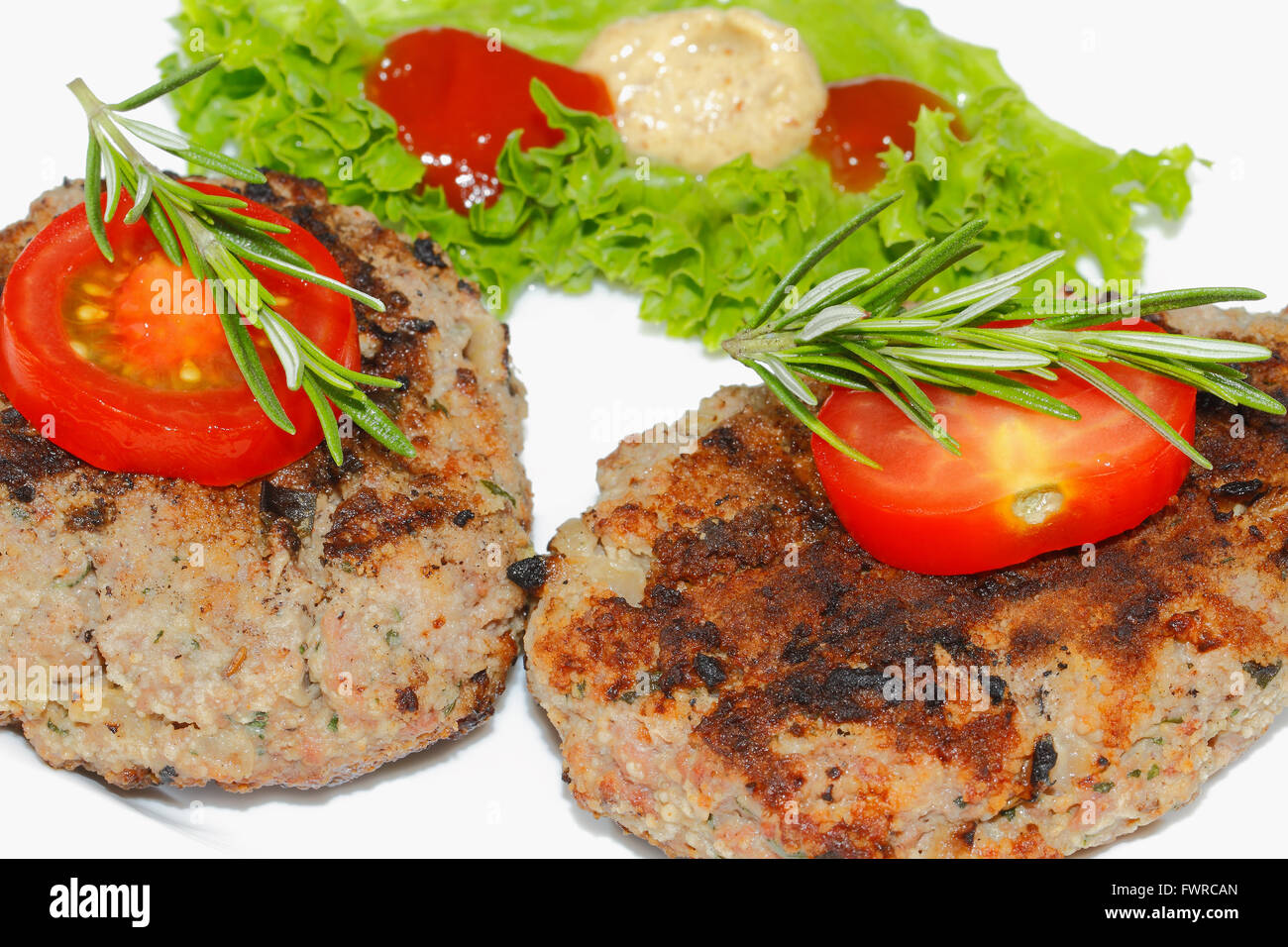 Grilled beef patties, garnished with sliced tomato and rosemary