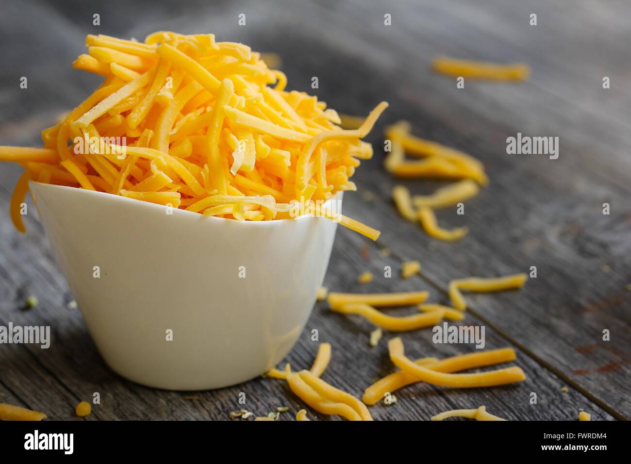 Shredded cheddar cheese in white cup  close up Stock Photo