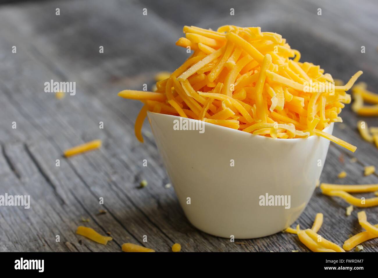 Shredded cheddar cheese in white cup close up Stock Photo Alamy