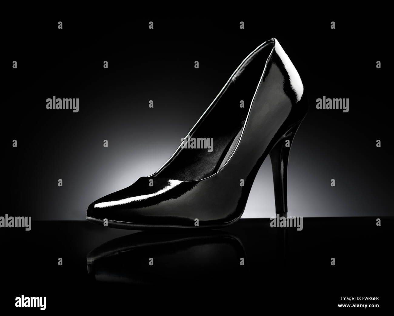 Black glossy ladies stiletto heel pump on black reflective background. Stock Photo