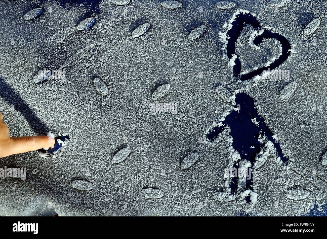Bonhomme and heart drawn in the frost on blue background Stock Photo