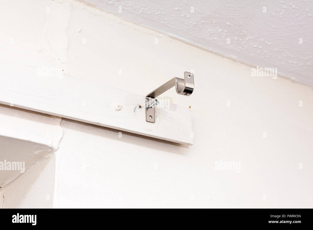 A metal curtain rail bracket put up on a wall with a screw Stock Photo