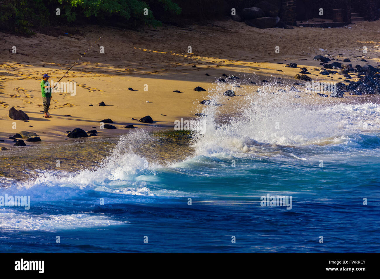 man fishing with rod off sandy beach Maui Hawaii Stock Photo
