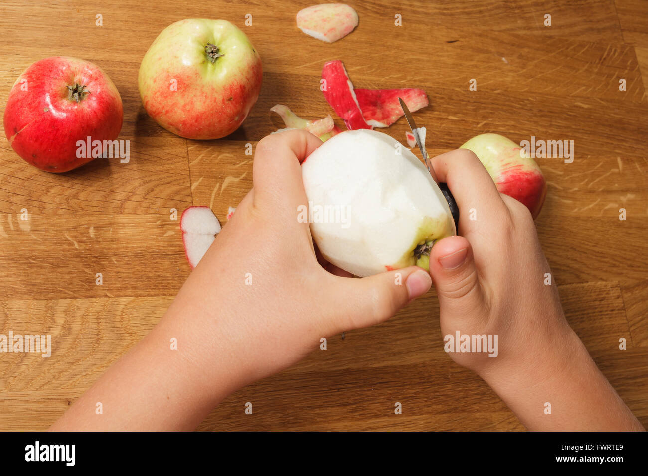Hands of a child peel an apple Stock Photo