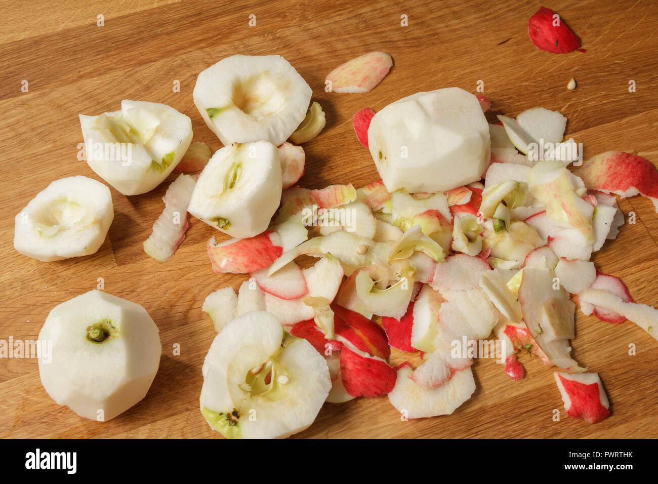 Pile of peeled apples and apple peel on a wooden table Stock Photo