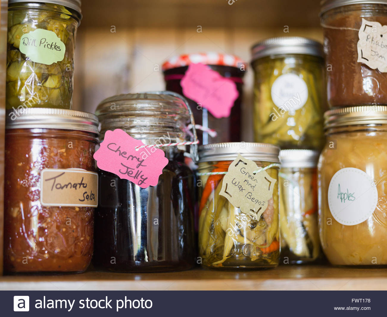 Fresh jam, pickled vegetables and canned fruits on shelf Stock Photo