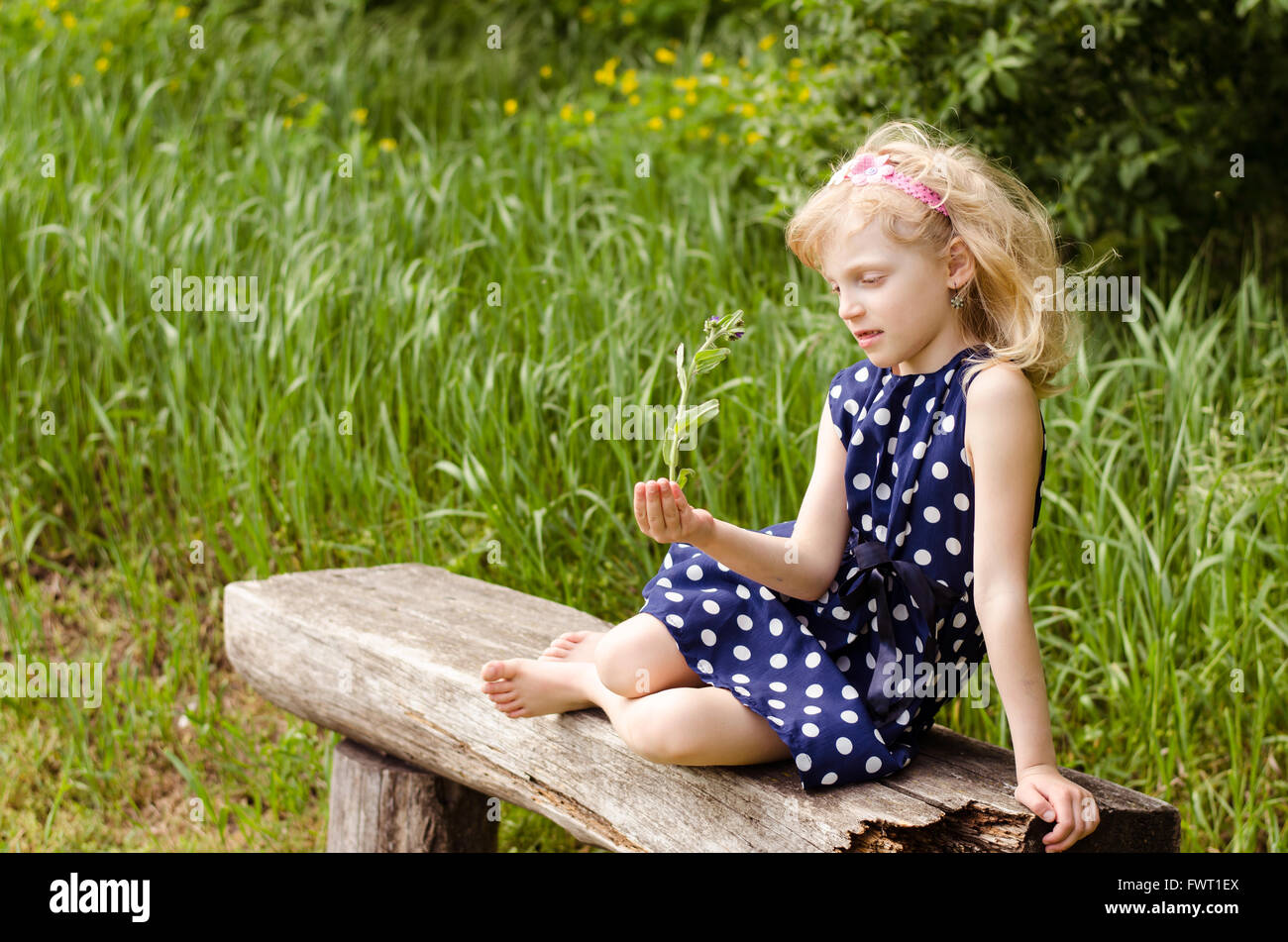 beautiful blond girl with closed eyes sitting on bench and posing Stock ...